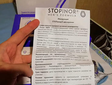 Инструкция и упаковка Stopinor для мужчин в руке крупным планом.